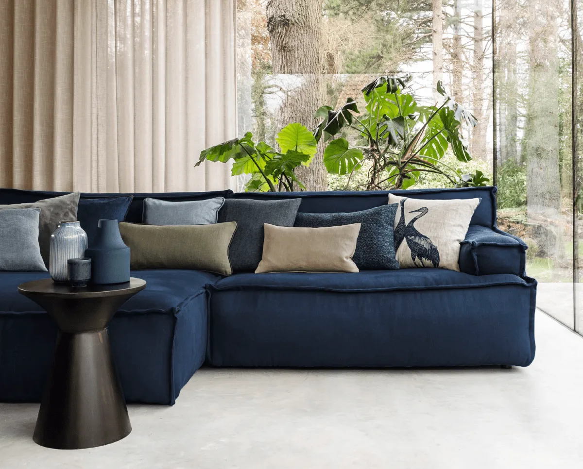 Blaue Couch in gemütlichem Wohnzimmer vor großer Fensterfront